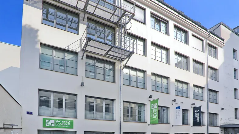 Modernes Bürogebäude mit weißer Fassade, vielen Fenstern und externer Metalltreppe.