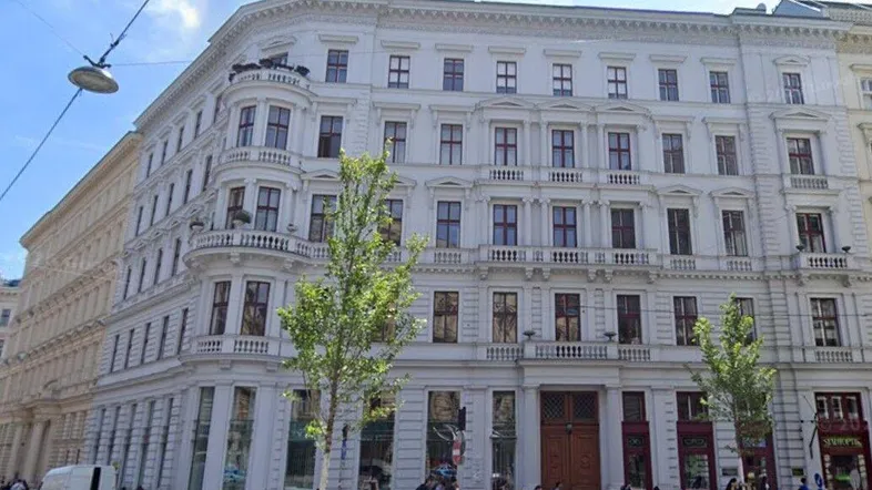 Historisches Gebäude mit klassischer Architektur und vielen Fenstern in einer städtischen Umgebung.