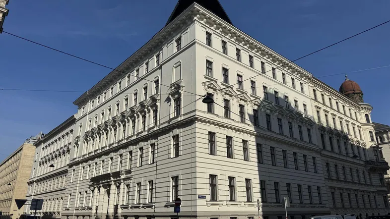 Historisches Eckgebäude mit klassischer Architektur und vielen Fenstern an einer städtischen Straße.
