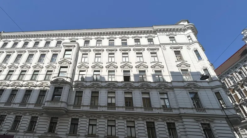 Die prächtige weiße Fassade des historischen Gebäudes mit vielen Fenstern und architektonischen Details unter blauem Himmel.