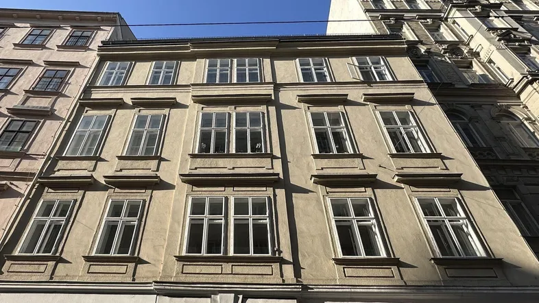 Historisches Gebäude mit mehreren Stockwerken und vielen Fenstern unter blauem Himmel.