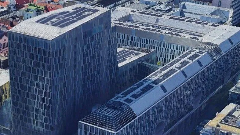 Luftaufnahme moderner Bürogebäude mit Glasfassaden und Photovoltaikanlagen auf den Dächern in einer städtischen Umgebung.