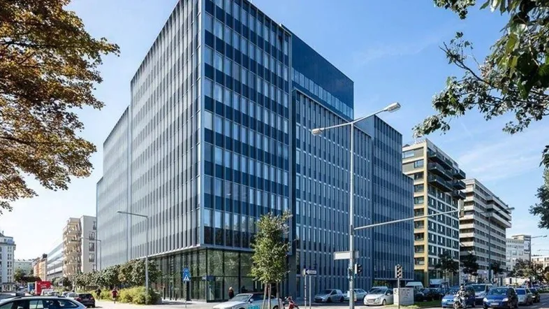 Modernes Bürogebäude mit Glasfassade und umliegender Straße unter blauem Himmel.