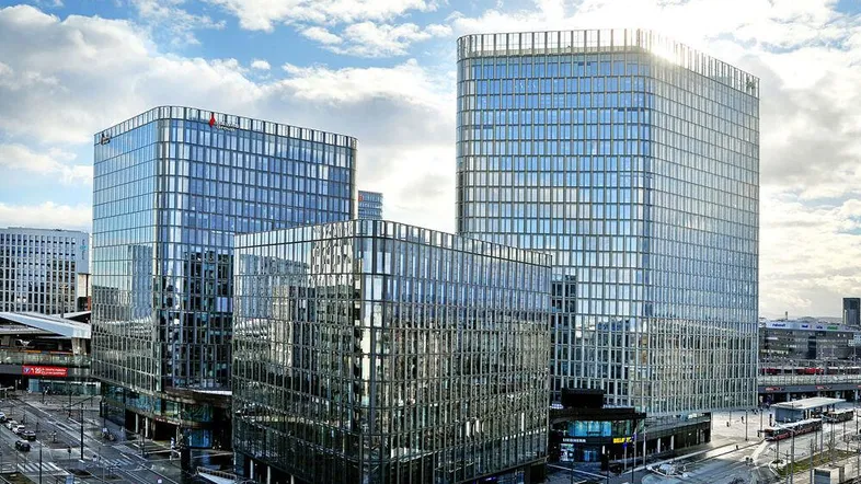 Moderne Bürogebäude mit Glasfassaden unter einem bewölkten Himmel in einer städtischen Umgebung.