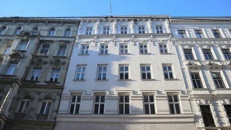 Klassische Fassade eines Mehrfamilienhauses mit vielen Fenstern und traditionellen architektonischen Details in der Stadt.