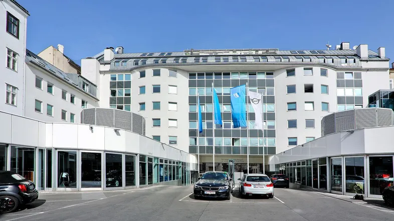 Moderne Geschäftsfassade mit großen Fenstern und einem Vorplatz, der als Parkbereich dient.
