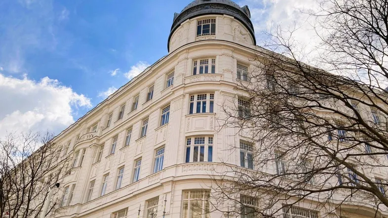 Historisches Gebäude mit eleganter Fassade und markantem Turm unter blauem Himmel.