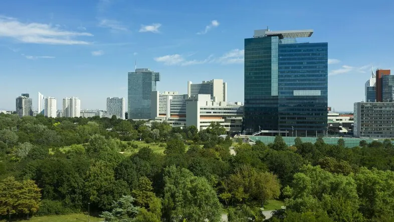 Panoramablick auf die Stadt mit modernen Hochhäusern und einem weitläufigen grünen Park im Vordergrund.