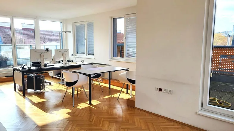 Helles Büro mit Fischgrätparkett, großen Fenstern und Zugang zu einer Terrasse.