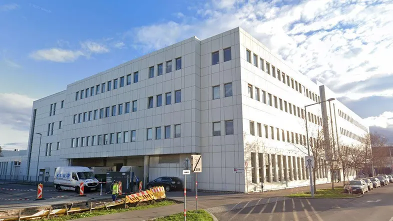 Modernes Bürogebäude mit weißer Fassade und vielen Fenstern an einer städtischen Straße.