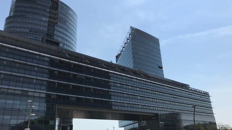 Moderne Bürogebäude mit Glasfassaden und markanter Architektur unter blauem Himmel, die eine städtische Landschaft prägen.