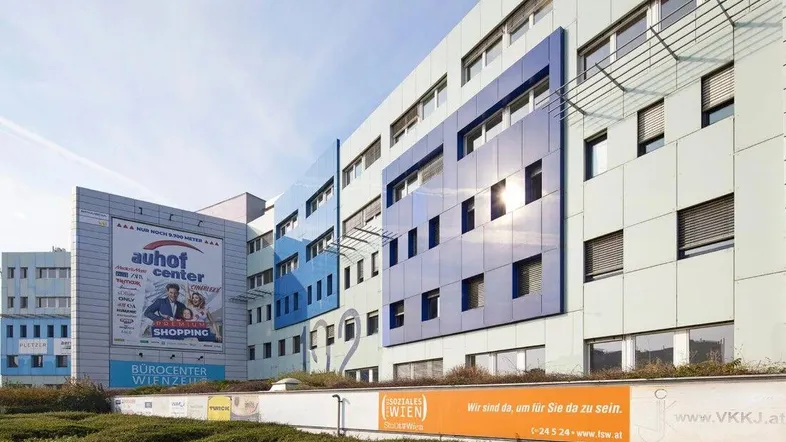 Modernes Bürogebäude mit blauen Fassadenelementen und großen Fenstern unter klarem Himmel.