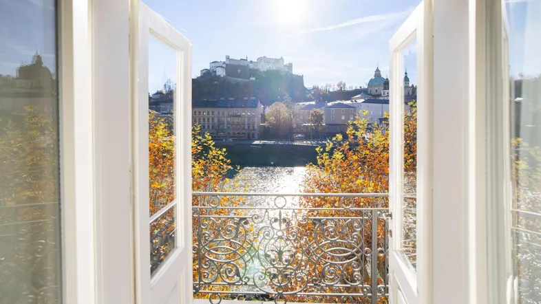 Heller Balkon mit schmiedeeisernem Geländer und malerischem Blick auf die Stadt, den Fluss und die Festung.