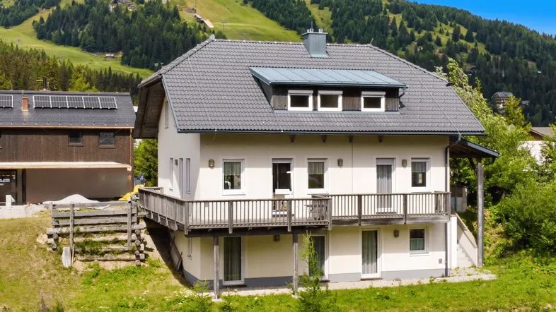 Hausfassade mit mehreren Balkonen und Blick auf die umliegende Berglandschaft.