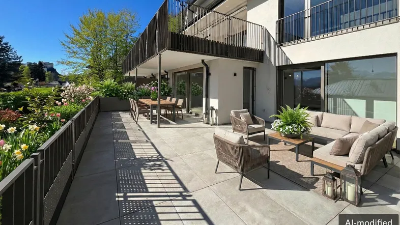 Große, möblierte Terrasse mit Essbereich und Lounge-Möbeln, umgeben von Pflanzen und mit Blick ins Grüne.