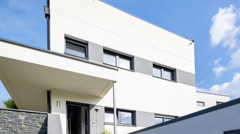 Moderne Architektur mit weißer und grauer Fassade, einladendem Eingangsbereich und Steindetails.
