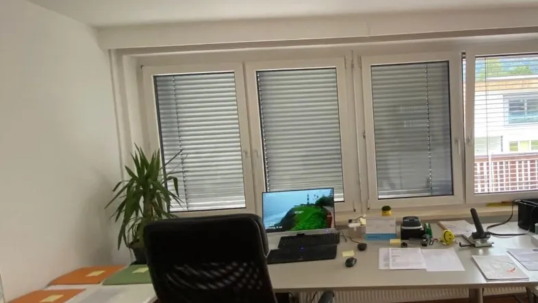 Helles Büro mit mehreren Fenstern, Schreibtisch und Bürostuhl, ideal für produktives Arbeiten.