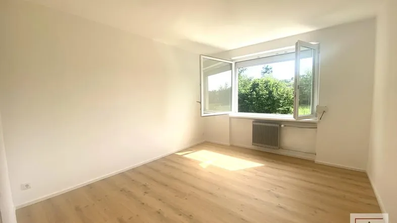 Helles Zimmer mit neuem Laminatboden und Blick ins Grüne, ideal als Wohn- oder Schlafzimmer.