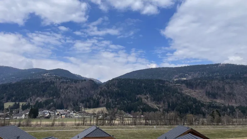 Panoramablick auf die umliegende Berglandschaft mit traditionellen Häusern im Vordergrund.
