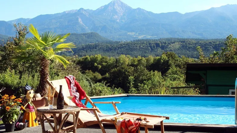 Entspannungsbereich im Garten mit Pool, Liegestuhl und atemberaubendem Bergblick.