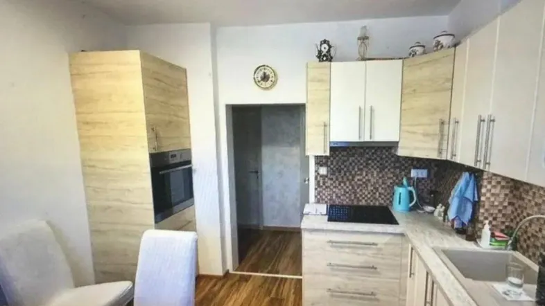 Helle Küche mit Holzoptik-Schränken, integriertem Backofen und modernem Fliesenspiegel.