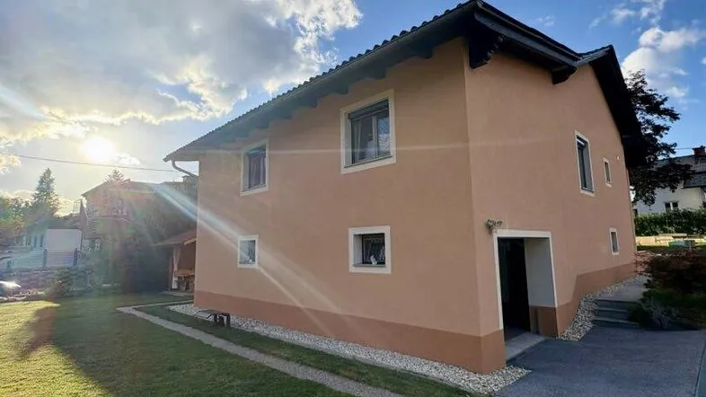 Einfamilienhaus mit gepflegtem Rasen und sonnigem Vorgarten unter blauem Himmel.