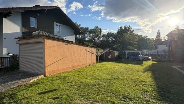 Großer Rasenbereich vor dem Haus mit Garage unter strahlend blauem Himmel.