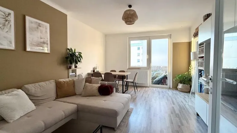 Heller, offener Wohn- und Essbereich mit modernem Laminatboden und Zugang zum Balkon.