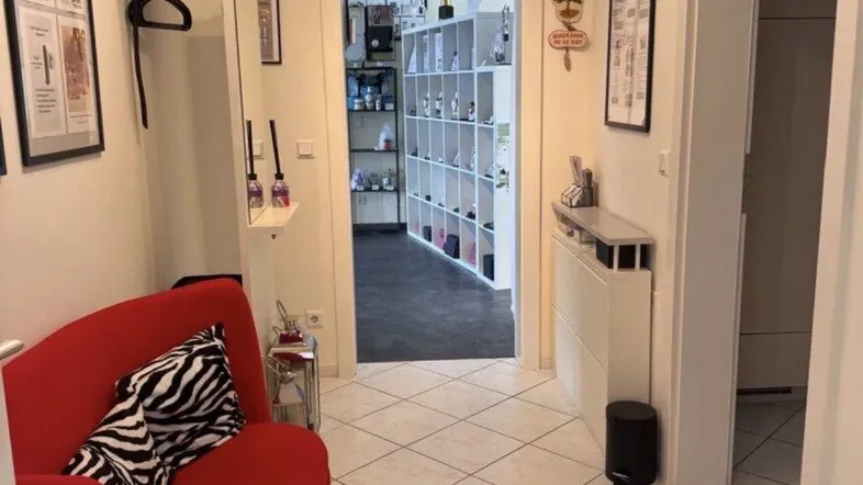 Heller Flur mit rotem Sofa, Spiegelgarderobe und Blick in einen weiteren Raum.