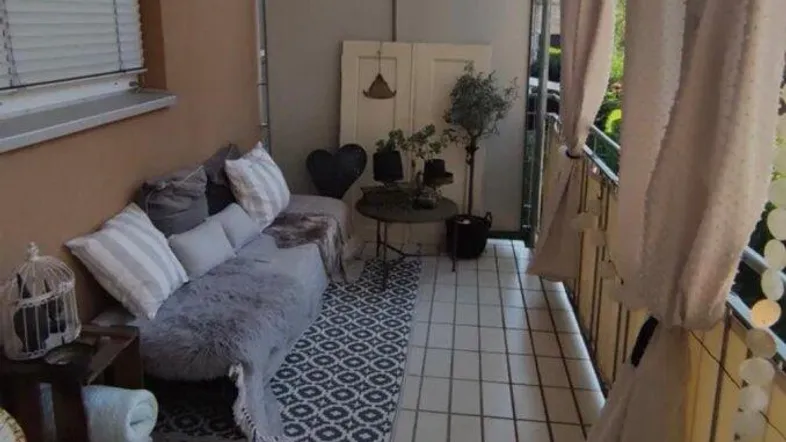 Gemütlicher Balkon mit Sitzgelegenheiten, Pflanzen und Fliesenboden, ideal zum Entspannen im Freien.