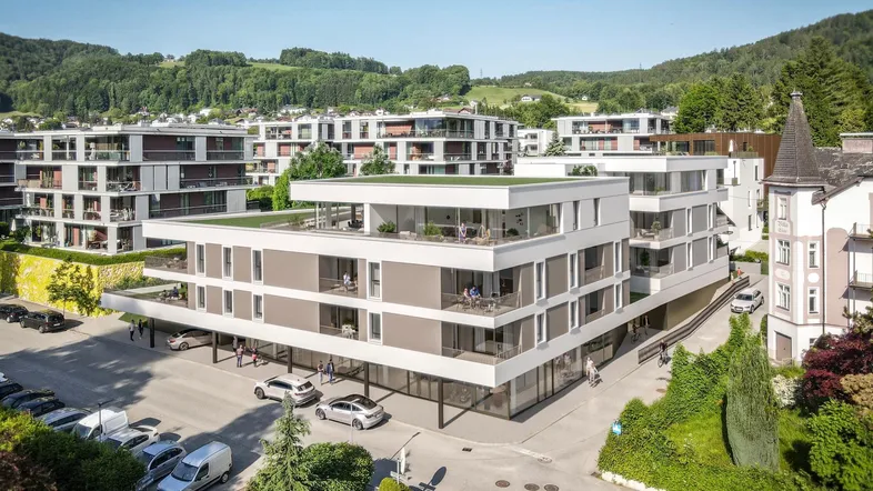 Moderne Wohnanlage mit Flachdächern und begrünten Terrassen in hügeliger Landschaft.