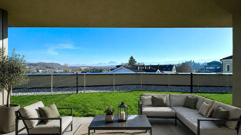 Möblierte Terrasse mit bequemen Sitzgelegenheiten, Rasenfläche und weitem Bergblick.