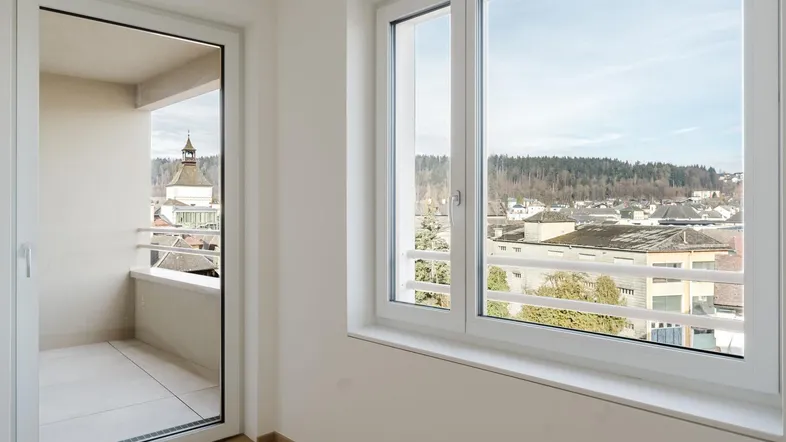 Helles Zimmer mit Zugang zum Balkon und weitem Blick über die Stadt und Landschaft.