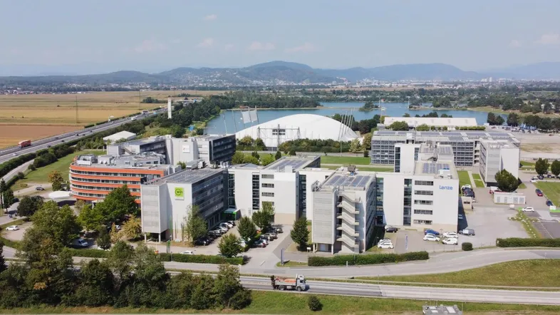 Luftaufnahme eines modernen Bürokomplexes mit umliegender Landschaft, See und Autobahn.