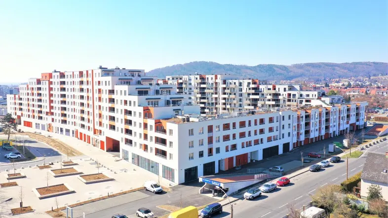 Eine Luftaufnahme eines modernen Wohnkomplexes mit mehreren Gebäuden und umliegenden Straßen unter blauem Himmel.