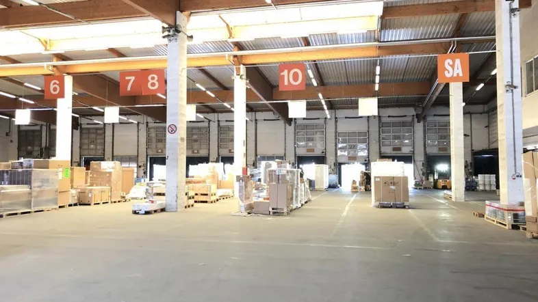 Geräumige Lagerhalle mit hohen Decken, Betonboden und mehreren Laderampen für effiziente Logistik.