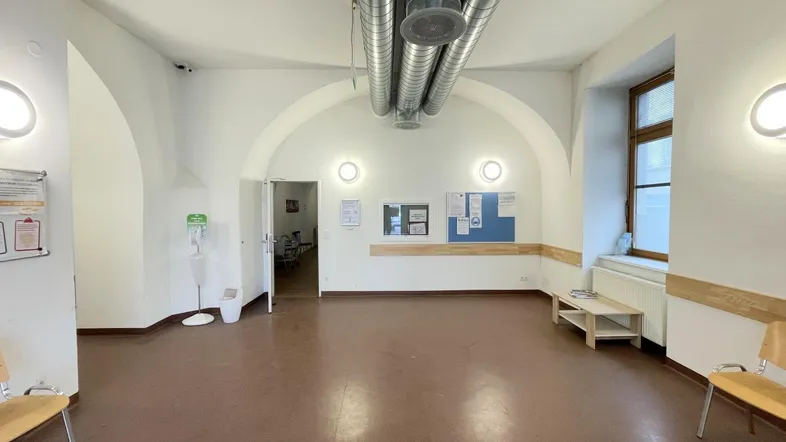 Geräumiger Empfangsbereich mit Gewölbedecke, braunem Boden und sichtbaren Lüftungsrohren.