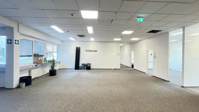 Geräumiges, leeres Büro mit Teppichboden, großen Fenstern und abgehängter Decke, bereit zur Nutzung.