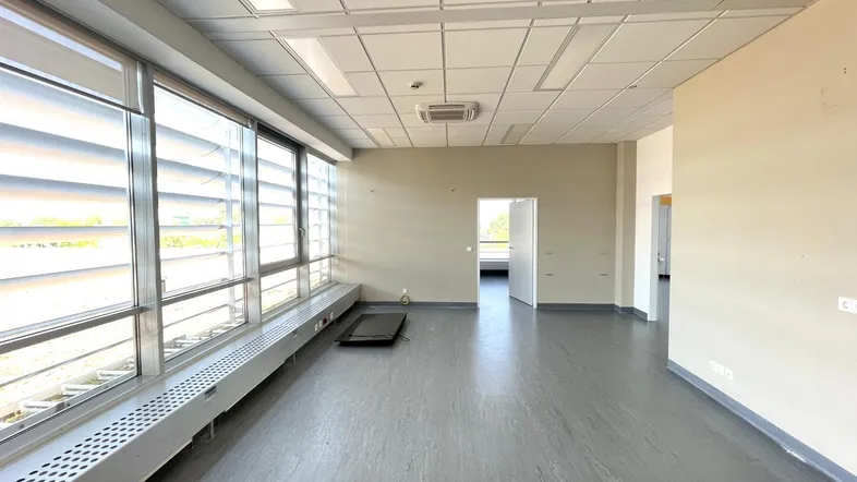 Geräumiger, leerer Büroraum mit großen Fenstern, die viel Tageslicht hereinlassen und einen weiten Blick bieten.