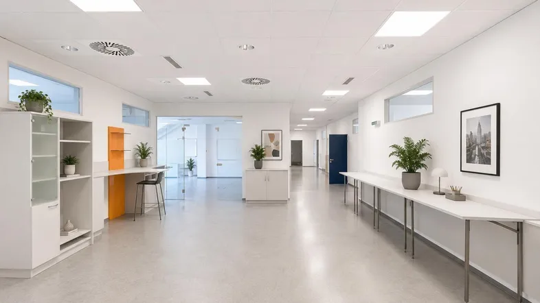 Helle und moderne Bürofläche mit langen Tischen, Pflanzen und viel natürlichem Licht.