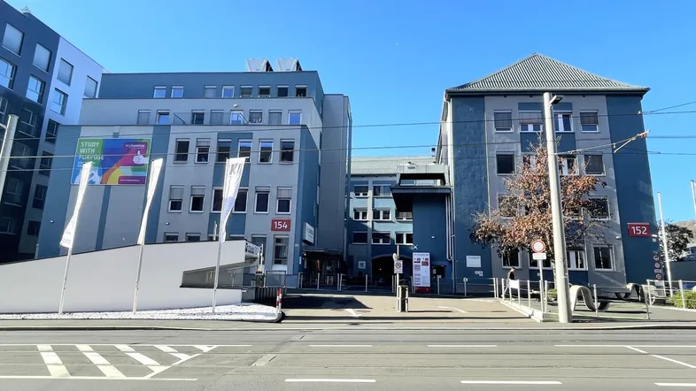 Moderne Bürogebäude mit mehreren Etagen und großen Fenstern an einer belebten Straße.