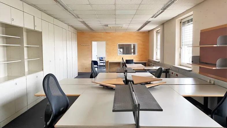 Großes Büro mit mehreren Arbeitsplätzen, Einbauschränken und einer orangefarbenen Akzentwand.