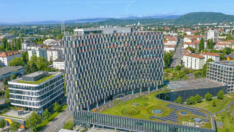 Luftaufnahme eines modernen Bürokomplexes mit begrünter Dachfläche und städtischer Umgebung.