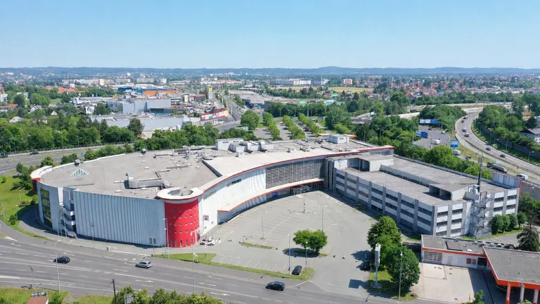 Luftaufnahme eines großen Gewerbekomplexes mit weitläufigen Parkplätzen und umliegender Infrastruktur.