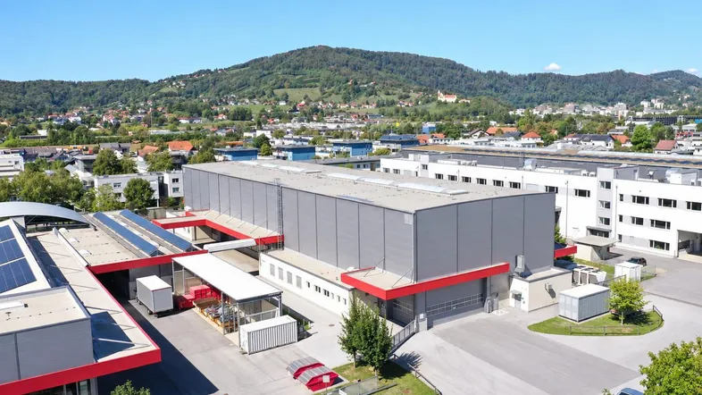 Luftaufnahme eines modernen Industriegebäudes mit Photovoltaikanlage und umliegender Landschaft.