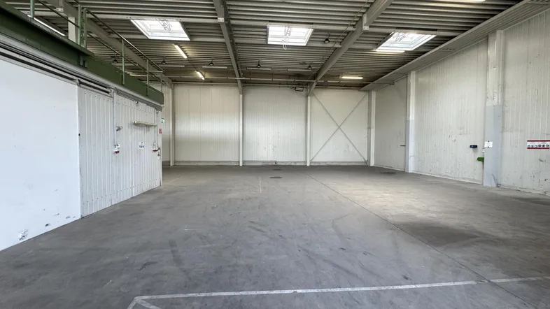 Große, leere Lagerhalle mit Betonboden und Oberlichtern, ideal für industrielle Nutzung.