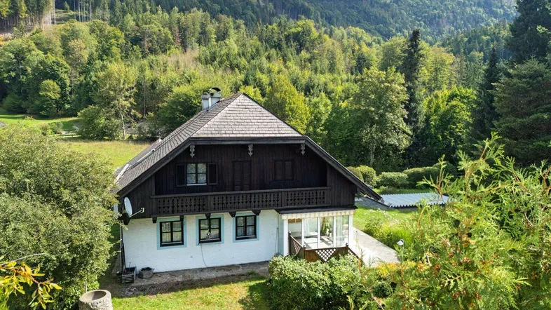 Traditionelles Haus in den Bergen mit umliegender Natur und grünem Garten.