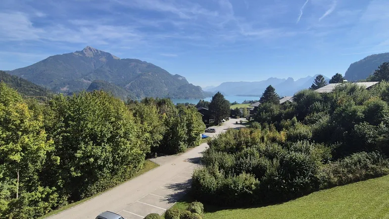 Atemberaubender Panoramablick auf majestätische Berge, einen glitzernden See und die umliegende grüne Natur.