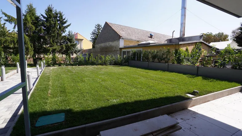 Großer, gepflegter Rasenbereich mit angrenzender Terrasse und Blick auf die umliegenden Gebäude.