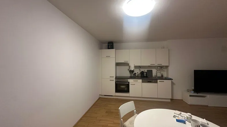 Offene Küchenzeile mit integrierten Geräten und Essbereich in einem hellen Wohnraum.